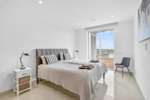 a white bedroom with a bed and a chair at Penthouse by the Marina in Lagos +26 photos