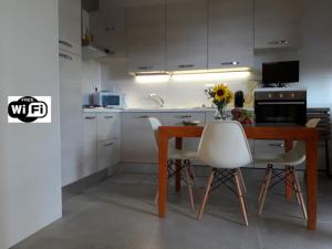a kitchen with a wooden table and white chairs at casa Fantulìn Mare in Laigueglia
