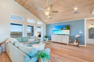 a living room with a blue couch and a flat screen tv at Horizon House Stay. Relax. Repeat. in Port Aransas