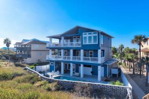 a blue house on the beach with palm trees at Horizon House Stay. Relax. Repeat. in Port Aransas