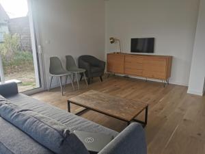 a living room with a couch and a tv and a table at Maison spacieuse - Perros Guirec in Perros-Guirec
