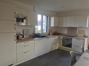 a white kitchen with white cabinets and a window at Maison spacieuse - Perros Guirec in Perros-Guirec