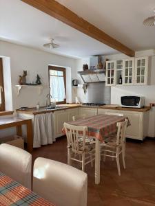 a kitchen with a table and chairs and a kitchen with white cabinets at Mezzodì Locazione Turistica in Colcerver