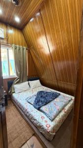 a small bed in a room with a wooden wall at Lanying Riverview Homestay in Dirang Dzong +55 photos