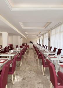a dining room with white tables and red chairs at Hotel Tiffany in Rimini +55 photos