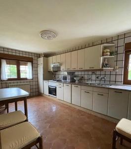 a kitchen with white cabinets and a table in it at Casa Las Coberazas in Arenas de Cabrales