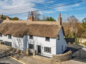an old white cottage with a thatched roof at Bridge Cottage in Bridport