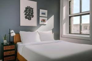 a white bed in a room with a window at The Alexander - Old Montreal in Montreal