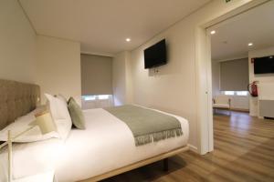 a bedroom with a large white bed and a television at Rossio Garden Suites in Lisbon
