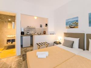 a bedroom with a large bed and a kitchen at 3 Goddesses' studios in Koukounaries