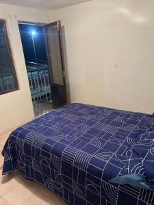 a bedroom with a bed with a blue and white blanket at Casa Fuentes in Zacatlán +1 photo