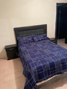 a bedroom with a bed with a blue comforter and pillows at Casa Fuentes in Zacatlán