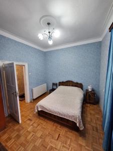 a bedroom with a bed with blue walls and wooden floors at Central Apartment Tskaltubo in Tsqaltubo +3 photos