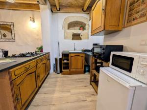 a kitchen with wooden cabinets and a white microwave at Gîte Val de Loire Le Puits in Loudun
