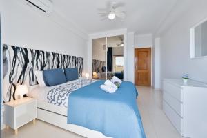 a white bedroom with a blue bed and a mirror at Casa Azul 3 - Senhora da Rocha, Algarve in Porches +25 photos