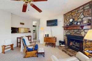 a living room with a stone fireplace with a couch and chairs at Misty Woods #4 in Sugar Mountain