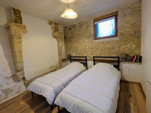 two beds in a room with a brick wall at Gîte Val de Loire Le Puits in Loudun