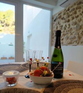 a bottle of wine and a bowl of fruit on a table at La Llar de la Font in Barraca de Aguas Vivas
