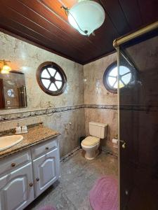 a bathroom with a toilet and a sink and a window at Hospedagem Flor de Alissah in Arraial do Cabo
