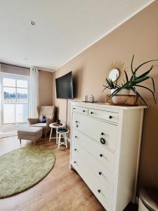 a room with a white dresser and a living room at Ferienzimmer Claudia in Surwold