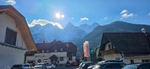 a small town with cars parked in front of mountains at River2Mountain Cozy Apartment in Gozd Martuljek