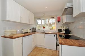 a kitchen with white cabinets and wooden counter tops at Stocks Barn in Liskeard +20 photos