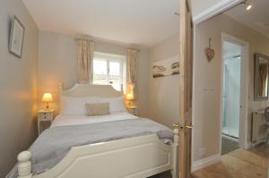 a bedroom with a white bed and a window at Stocks Barn in Liskeard