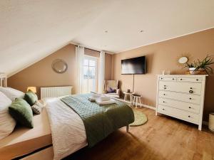 a bedroom with a bed and a dresser with a television at Ferienzimmer Claudia in Surwold