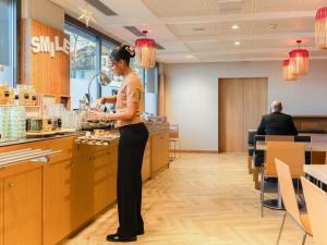 a woman standing at a counter in a restaurant at ibis Genève Petit Lancy in Geneva