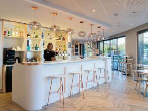 a woman standing at a bar in a restaurant at ibis Genève Petit Lancy in Geneva