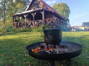 a pot over a fire on a grill in front of a cabin at Jesionowy Zakątek domki z balią blisko jeziora in Piasutno