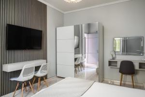 a bedroom with white furniture and a tv on a wall at Corfu City Center Design Residence incl private parking in Corfu