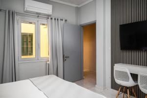 a bedroom with a bed and a desk and a television at Corfu City Center Design Residence incl private parking in Corfu