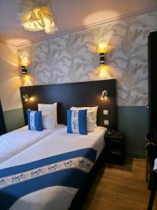 a bedroom with a large bed with blue and white pillows at Amadeus Hotel in Paris