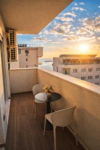 a balcony with a table and chairs and the sunset at Leonard's Shengjin Apartments in Lezhë