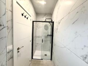 a shower in a bathroom with white marble walls at HAVELI Vinaros in Vinarós +15 photos