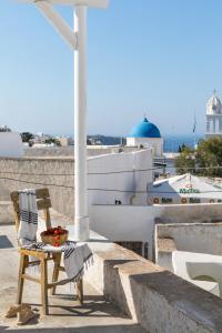 a chair and a bowl of fruit sitting on a ledge at Casa Grande Santorini in Megalochori