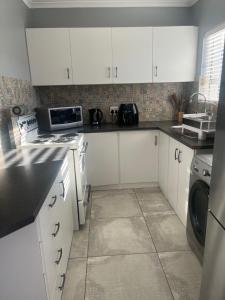 a kitchen with white cabinets and a washer and dryer at Flamingo Park D1 Langebaan in Langebaan