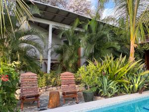 two wooden chairs sitting next to a swimming pool at Poolside Cabaña Studio with stunning ocean view in Puerto Escondido