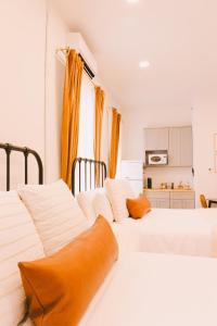 two white beds in a bedroom with orange pillows at The Historic Hattie House in Abingdon