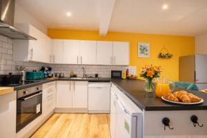 a kitchen with white cabinets and a plate of bread at Brighton Colour Pop House- Sleeps up to 12 in Brighton & Hove +23 photos