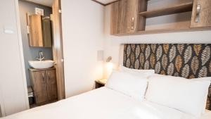 a small bedroom with a bed and a sink at 2. Supreme OD 2 Caravan with Decking in Ringwood