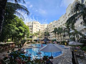 a resort with a swimming pool with an umbrella at Thermas Paradise Residence in Rio Quente