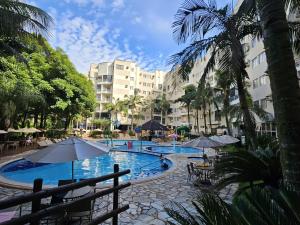 a swimming pool with tables and umbrellas and buildings at Thermas Paradise Residence in Rio Quente +38 photos