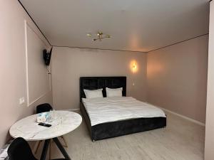 a small bedroom with a bed and two tables at Meridian Hotel in Almaty +5 photos