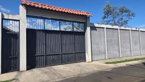 a house with a black gate and a fence at Apartamento Decrusi in Alajuela