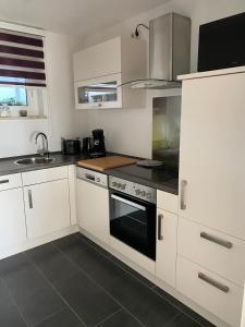 a kitchen with white cabinets and a black oven at Ferienwohnung Sonnenplatz in Fehmarn