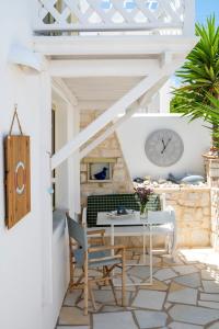 a patio with a table and chairs and a clock at Leonardos Apartments in Naousa