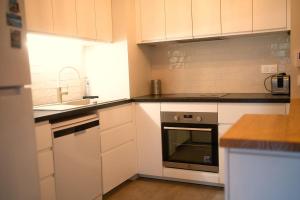 a kitchen with white cabinets and a sink and an oven at Grand appartement-lac-centre-hossegor in Hossegor