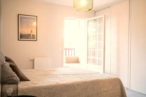 a white bedroom with a bed and a window at Grand appartement-lac-centre-hossegor in Hossegor